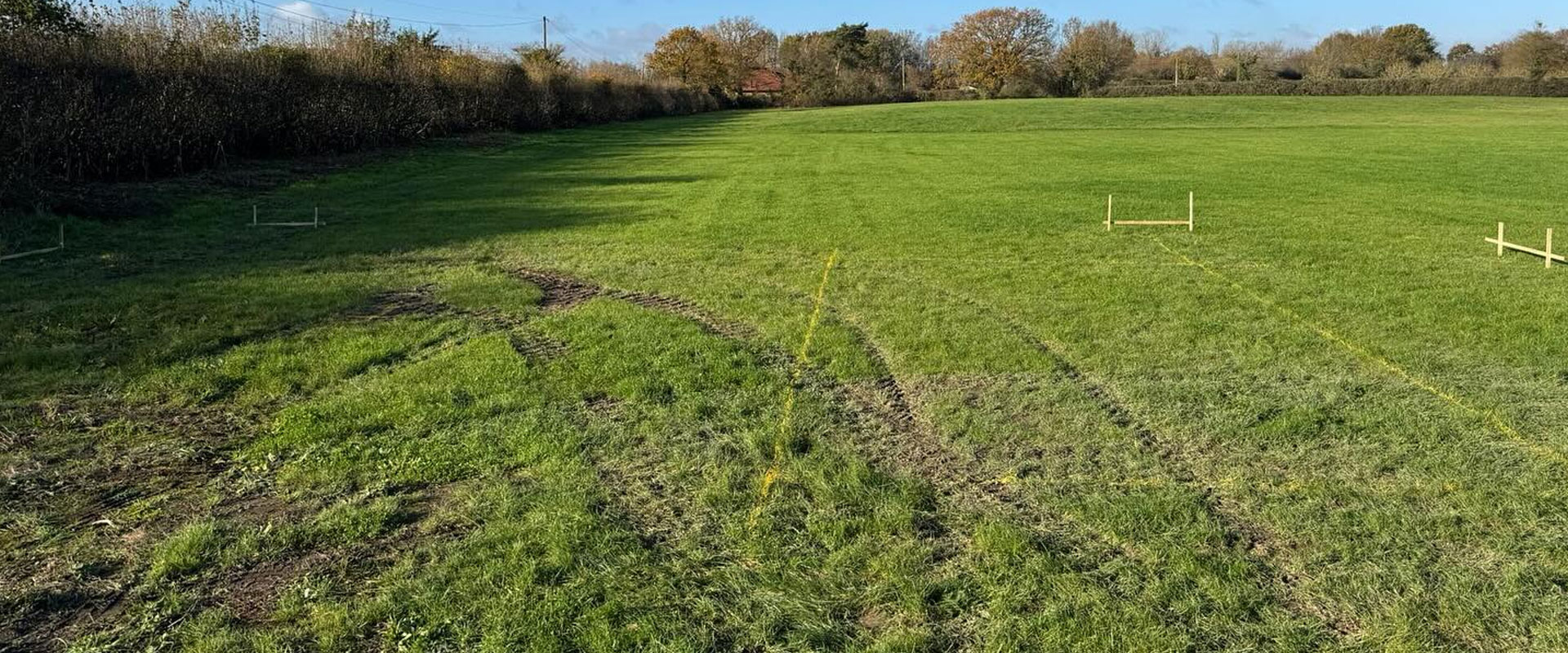 Open building plot with the outline of a new home marked out in pegs